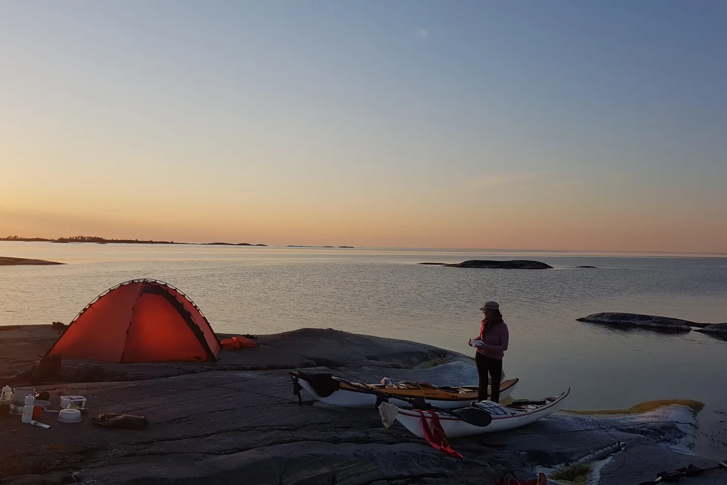 Campare i solnedgången i skärgården. Gult tält på en slät klippa