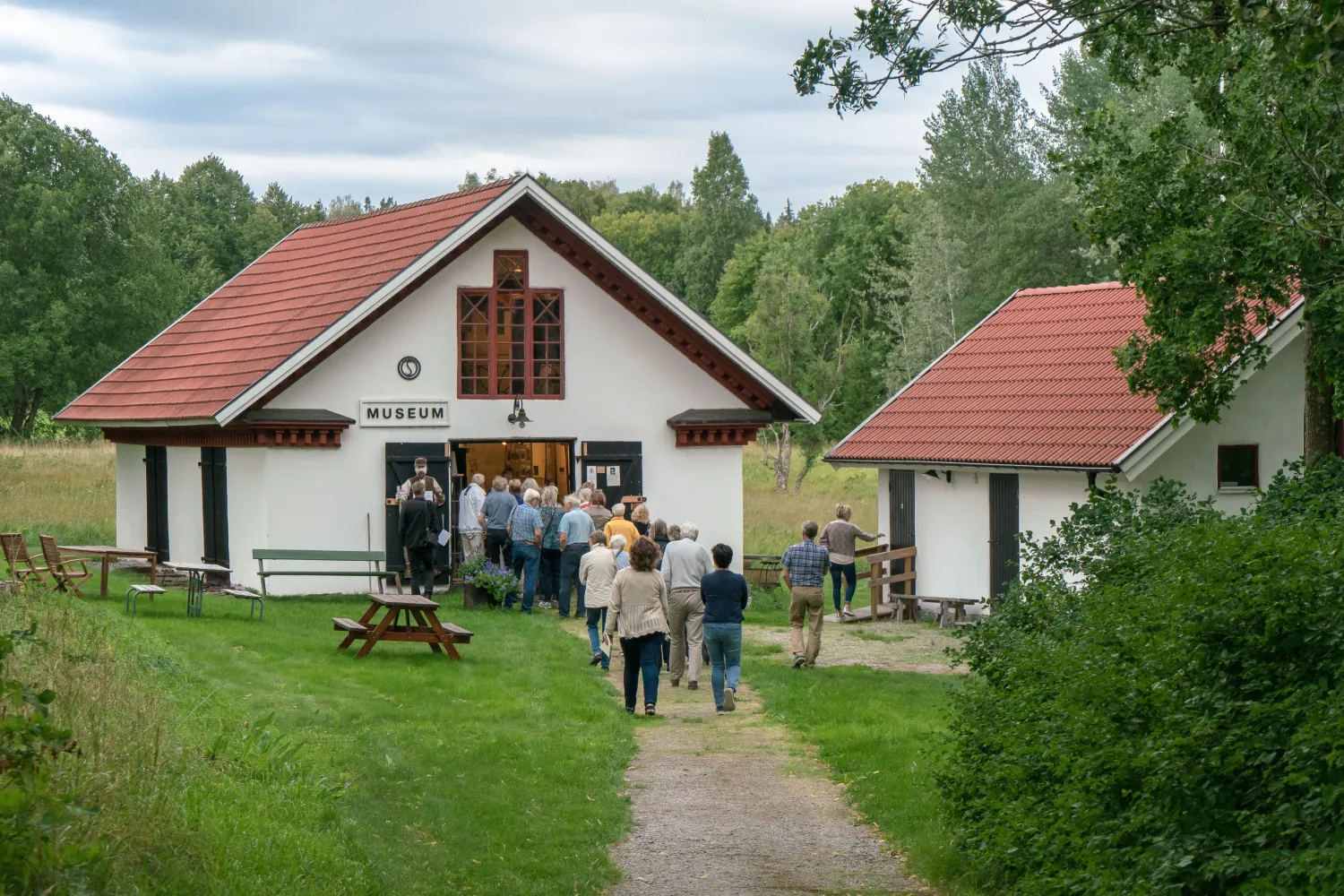 En grupp människor på väg in i en vitputsad byggnad med skylten Museum på väggen