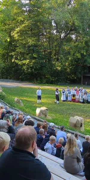 Utomhus teater med en stor publik i förgrunden och skådespelare i bakgrunden