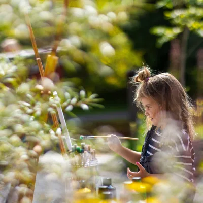 Flicla som målar på ett staffli i solen