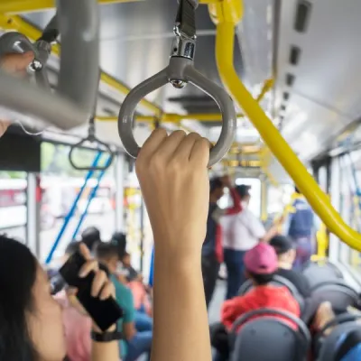 Full buss med pendelresenärer. Kvinna som håller i sig i taket.