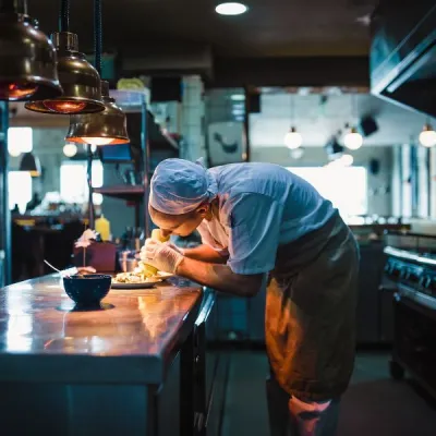 Serveringspersonal i restaurangkök som lägger på mat på tallriken