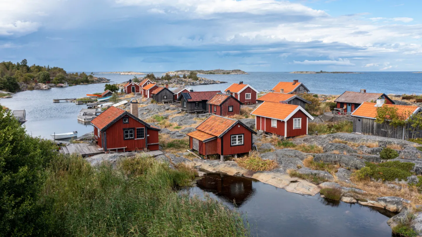 EN karg ö i ytterskärgården. Röda små stugor med tegeltak och vita eller svarta knutar.