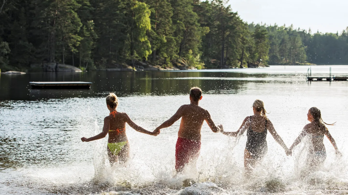 Badande ungdomar i en sjö med träd runt