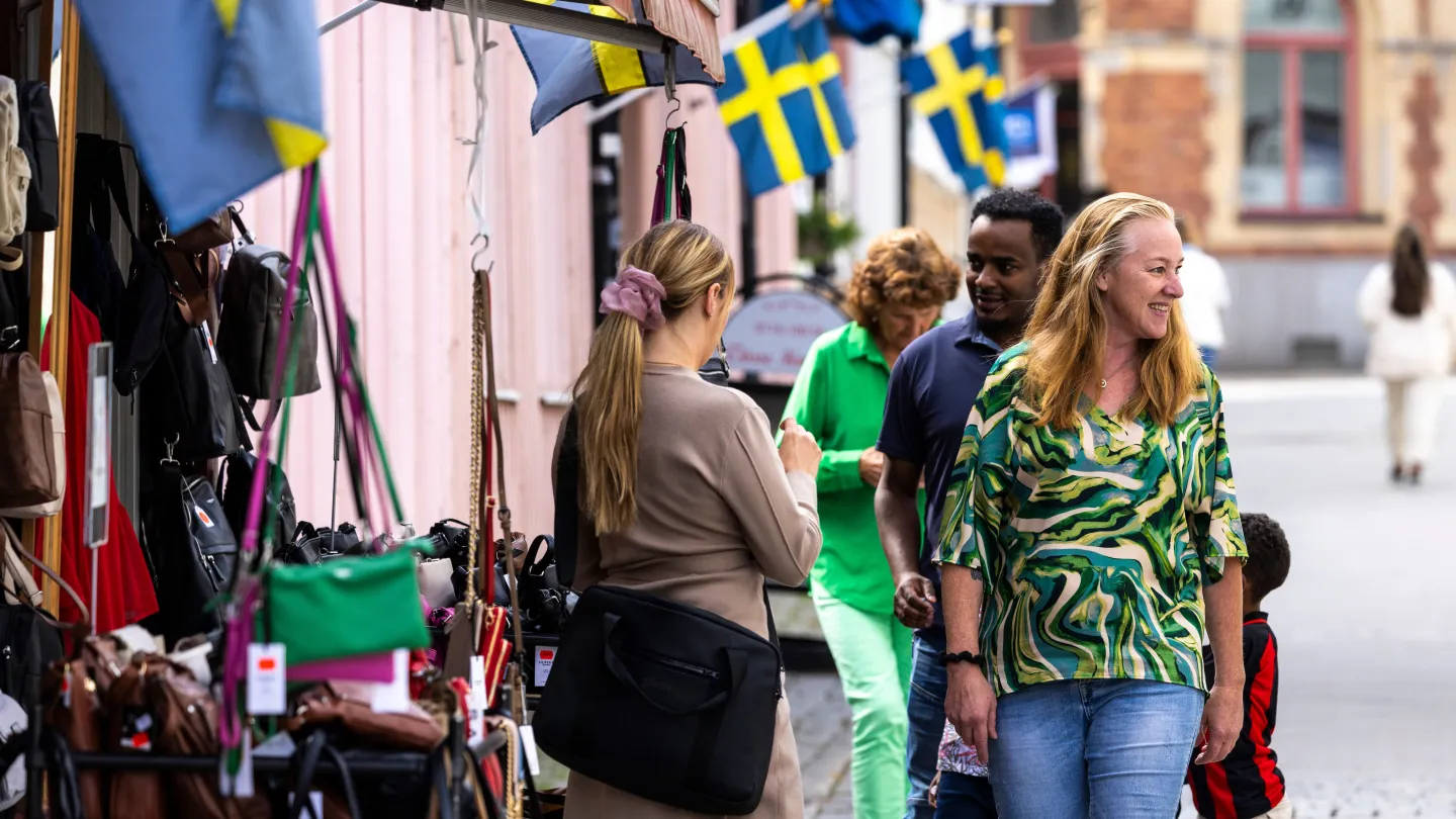 Folk på en gågata, utanför en väskaffär