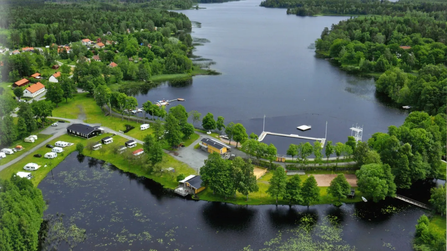 Drönarbild på en camping i skärgården. Gröna löv och blått vatten